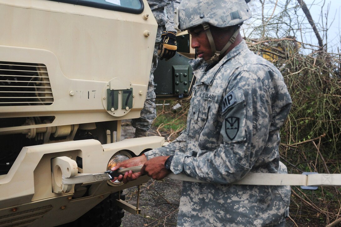 Cadet Charles Moorehead attaches a harness to a light medium tactical vehicle to move a down utility pole.