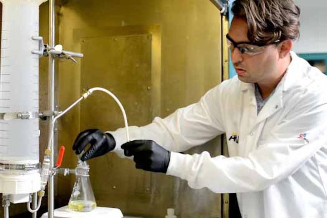 A scientist pours powder into a beaker of urine.