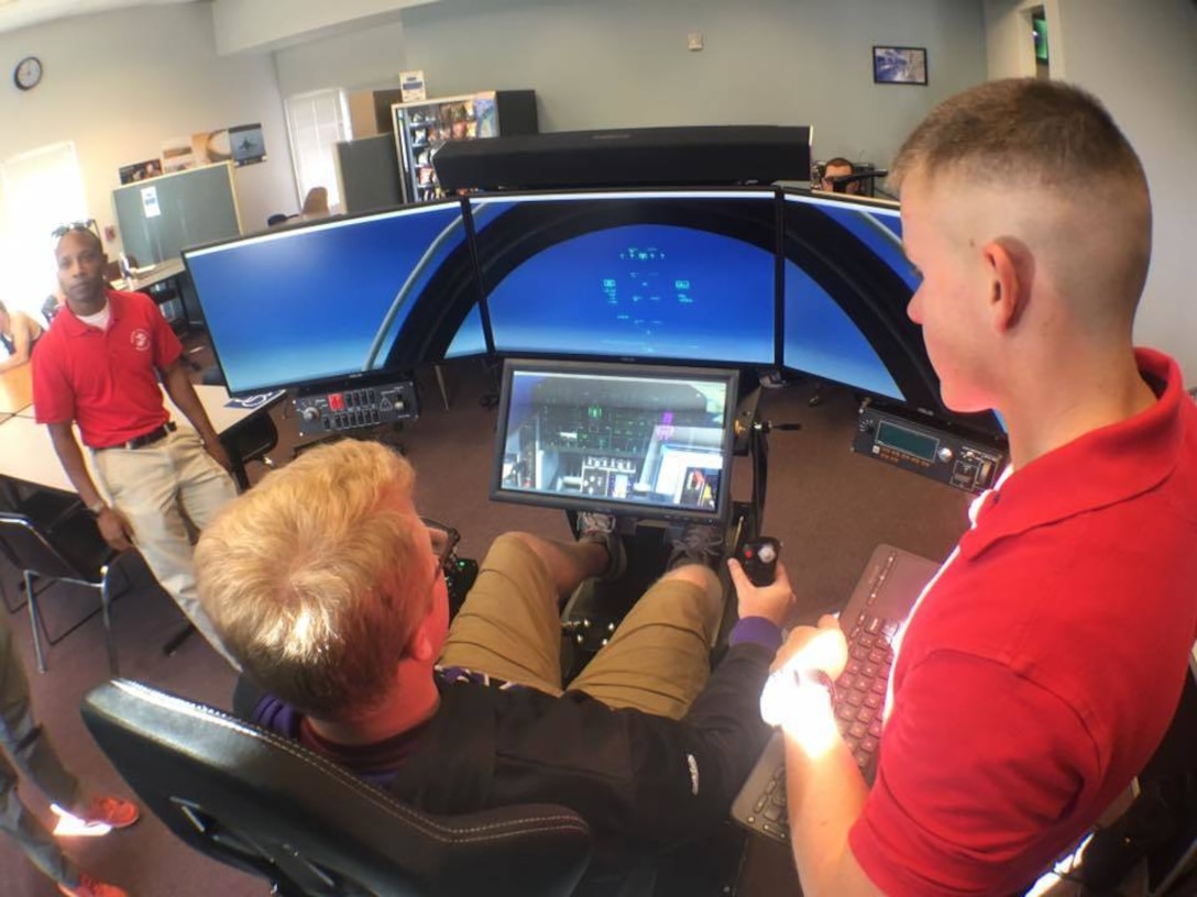 Capt. Anthony Rollins, an Officer Selection Officer with Recruiting Station Denver (left) and 2nd Lt. Shay Farrell, assist a Metro State University student on how to use a flight simulator in the Robert K. Moch World Indoor Airport at MSU Denver, Sept. 20, 2017. The flight simulator was included as part of a school visit to MSU in order to demonstrate possible career opportunities accompanied with becoming a Marine Corps officer.