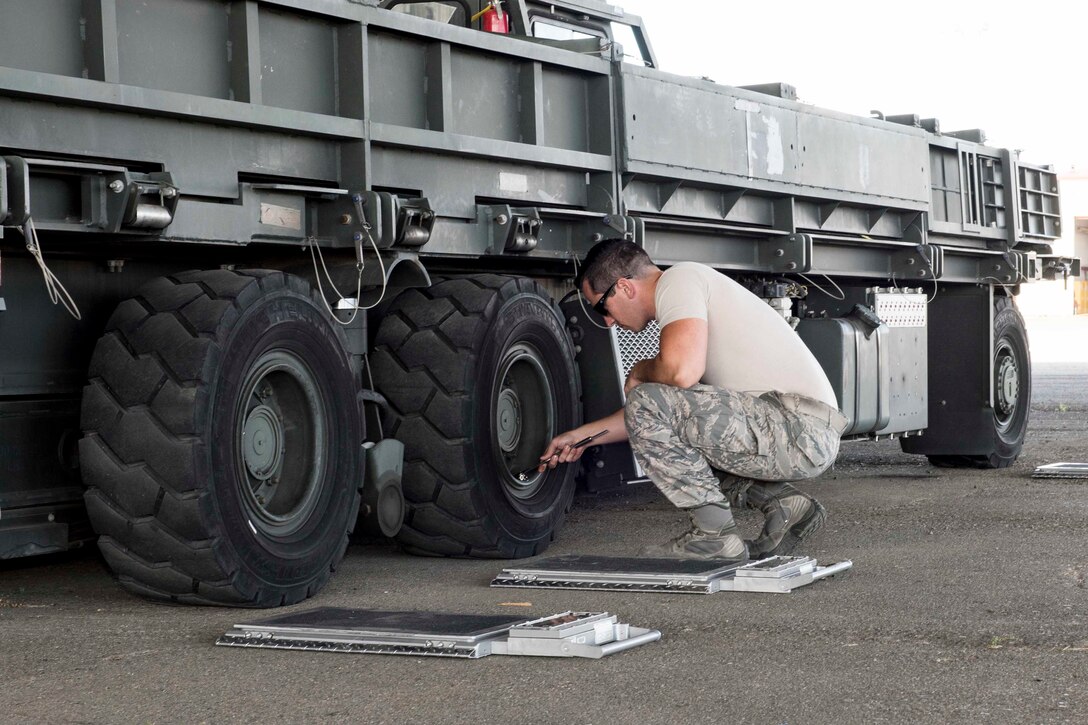 An airman checks the tire pressure on a truck.