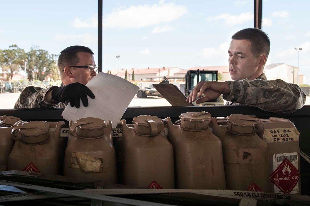 Two airmen take notes standing by a supply truck.