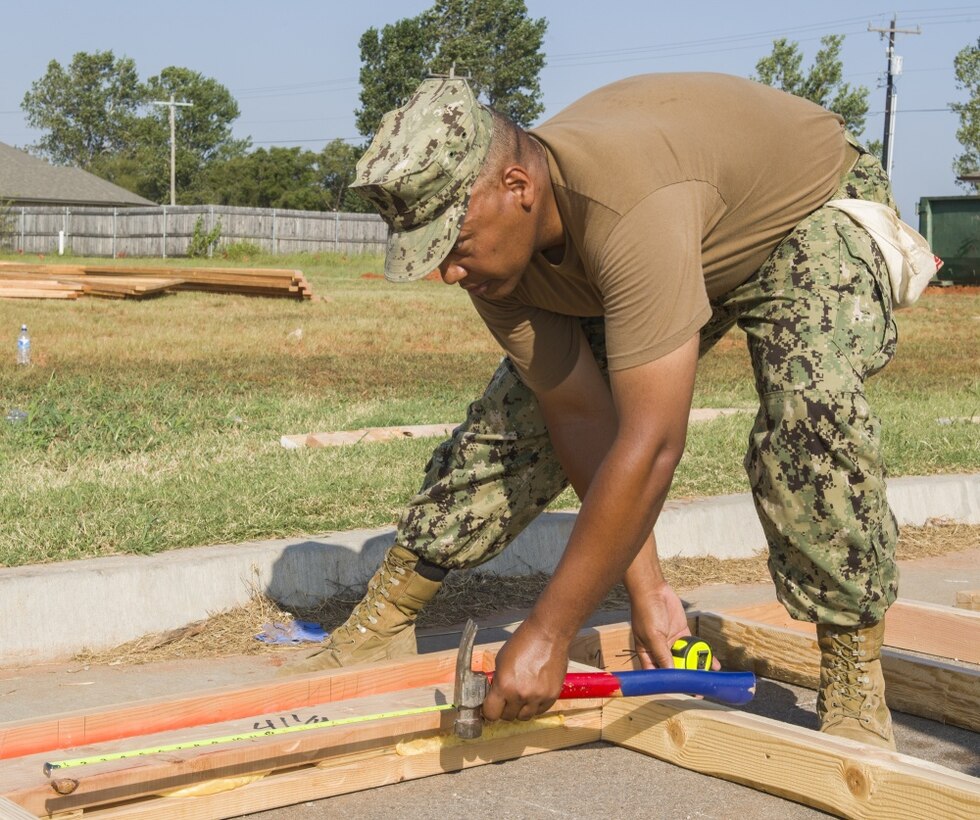 Navy Command Master Chief Delbert Terrell Jr. measures a window frame during a community outreach project.