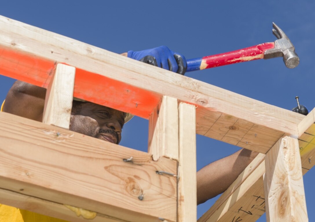 Navy Petty Officer 1st Class Lionel Brown, assigned to Commander Strategic Communications Wing 1, hammers a wall frame during a community outreach project.