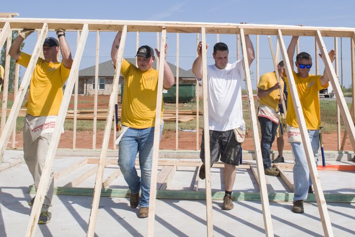 Four men lift a frame while building a house.