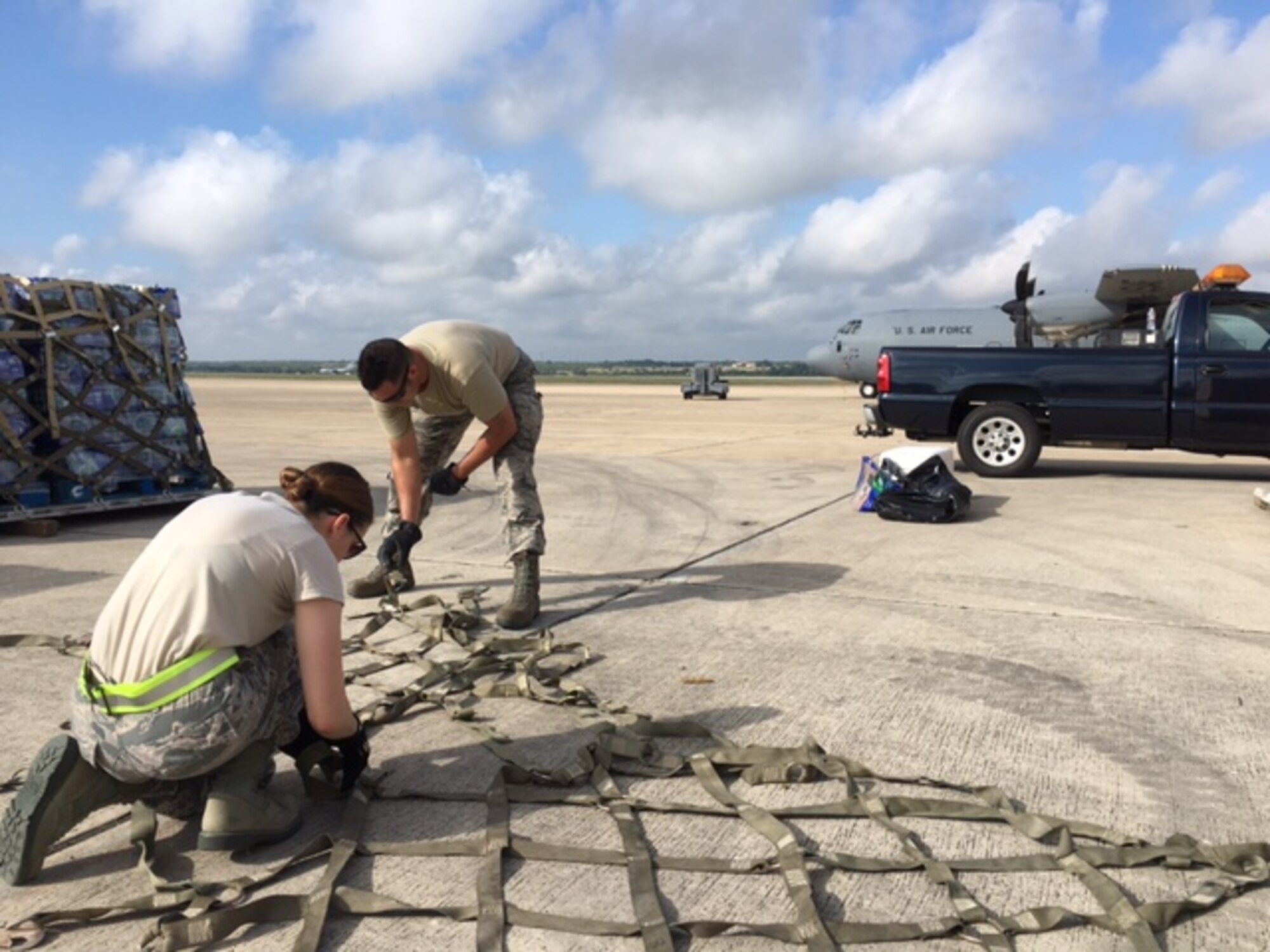 Senior Airman Sarah Nededog (fore) and Tech. Sgt. Antonio Montano, 502nd Logistics Readiness Squadron traffic management office, straighten out cargo straps to help prepare Hurricane Maria relief supplies for air transport Sept. 22, 2017 at Joint Base San Antonio-Kelly Field.  The supplies were being staged at the Federal Emergency Management Agency’s Incident Support Base at Kelly for transport to areas devastated by Hurricane Maria (U.S. Air Force image/Dan Hawkins)