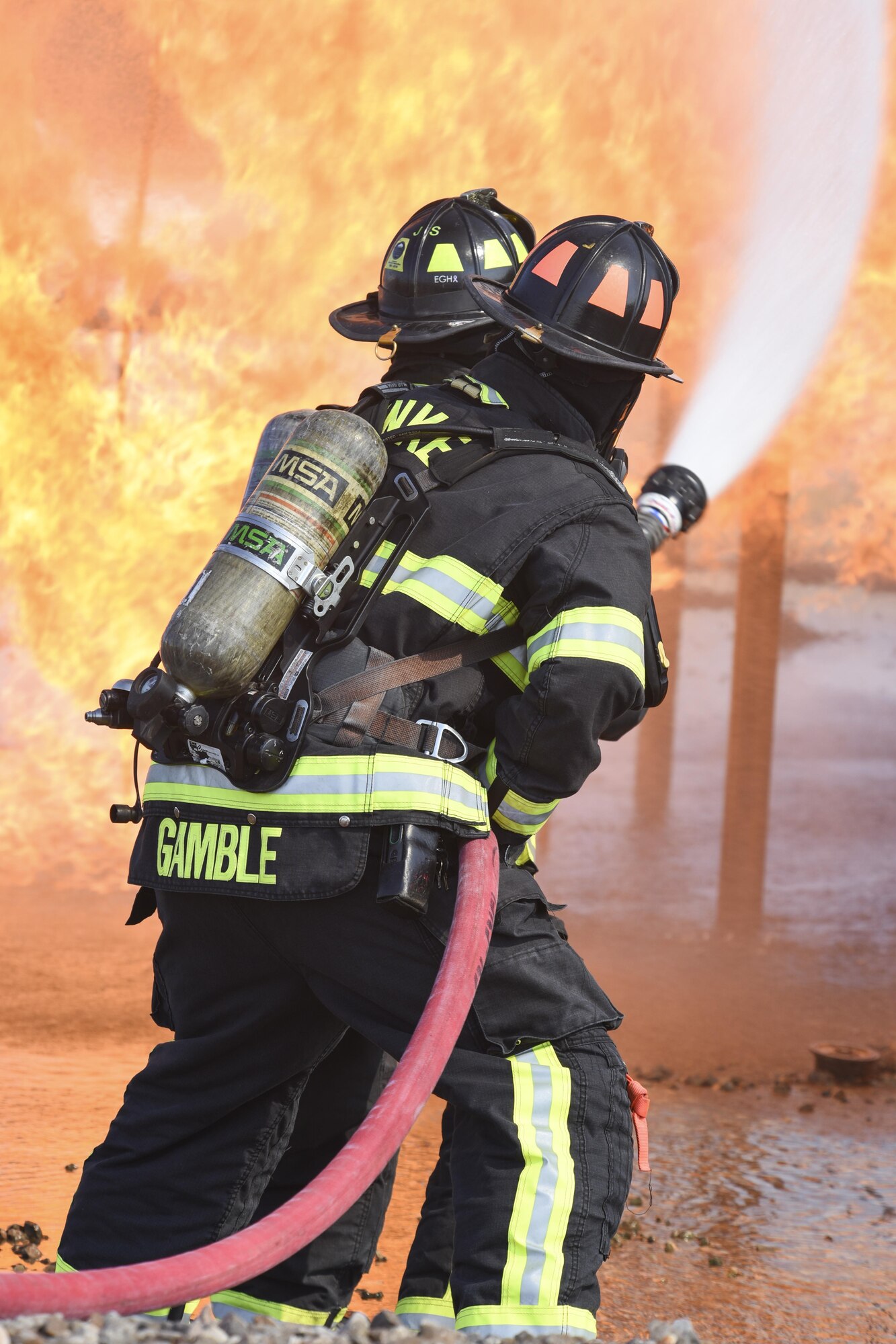 Two member teams from the 72nd Civil Engineer Squadron, fire department, work together as they approach the full-size aircraft fire training device Sept. 13, 2017, Tinker Air Force Base, Oklahoma. The firefighters were conducting annual  recertification training in the realistic environment.