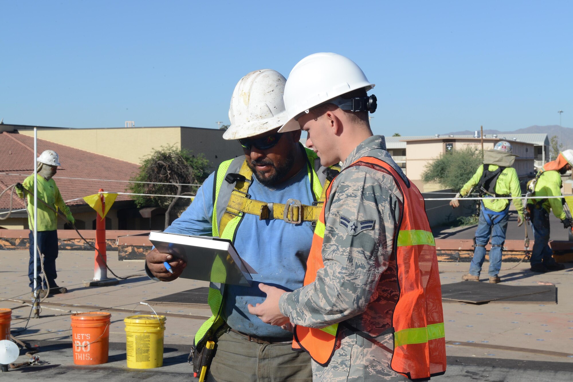 Airman 1st Class Dimitri Pfeifer, 56th Contracting Squadron contract specialist, performs a labor standards interview with Manuel Reyes, Starkweather Roofing Inc. foreman, at Luke Air Force Base, Ariz., Sept. 20, 2017. The labor standards interview was part of a site survey at the Security Forces Squadron rooftop. Pfeifer made sure the subcontractors and workers were receiving pay appropriate to the job. (U.S. Air Force photo by Senior Airman James Hensley)