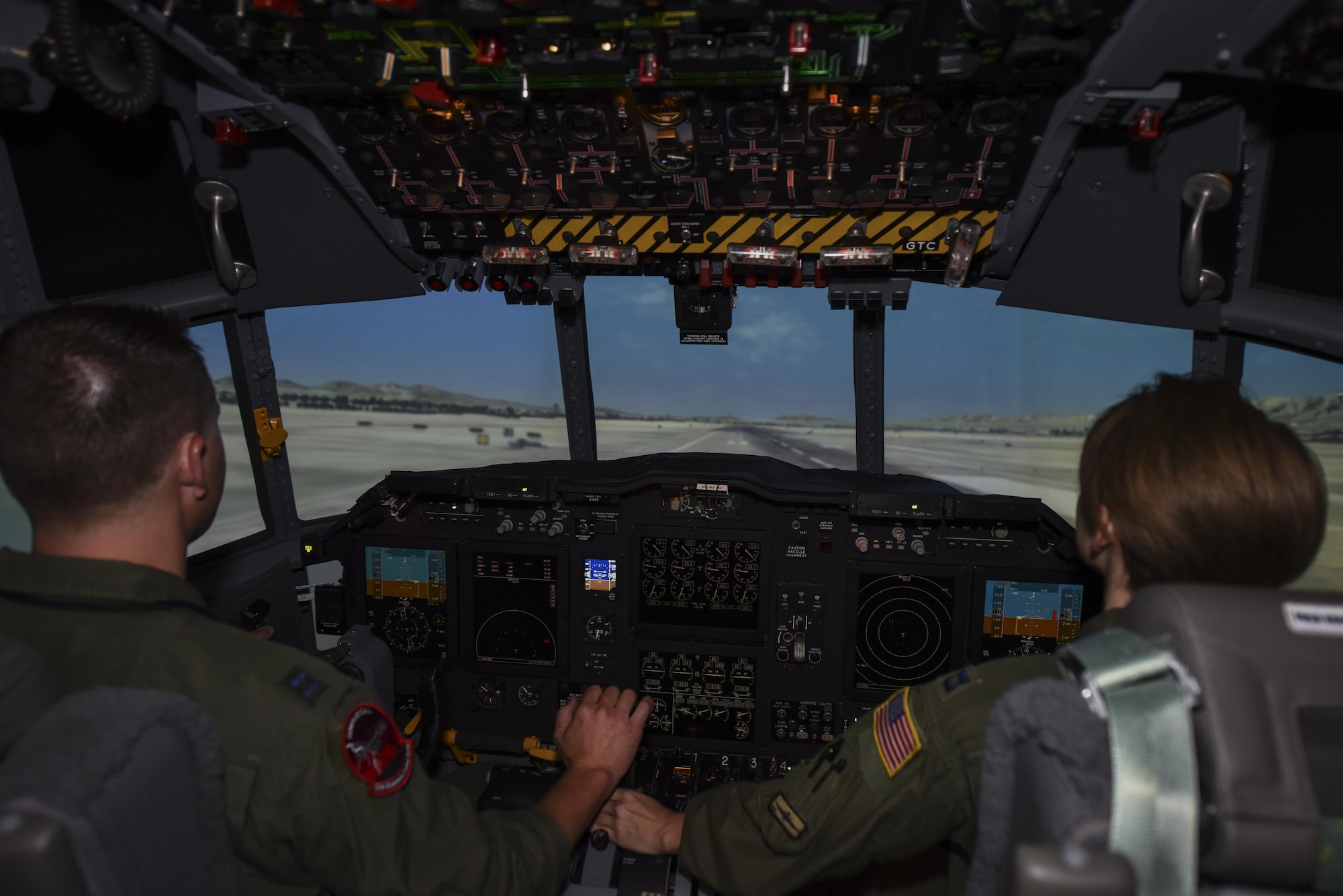 U.S. Air Force Capt. Brett Neilson, 55th Electronic Combat Group instructor, and Capt. Megan Russell, 42nd Electronic Combat Squadron evaluation pilot, simulate a landing of an EC-130H Compass Call at Davis-Monthan Air Force Base, Ariz., Sept. 22, 2017. The 42nd ECS flight simulator went through a $10.5 million upgrade to better prepare the pilots for their future flights.