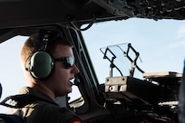 A pilot speaks into a microphone while sitting at the controls of an aircraft.
