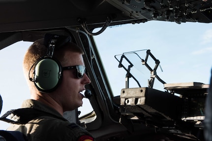 A pilot speaks into a microphone while sitting at the controls of an aircraft.
