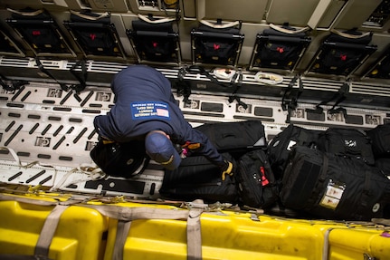 A person leans over to pick up bags.
