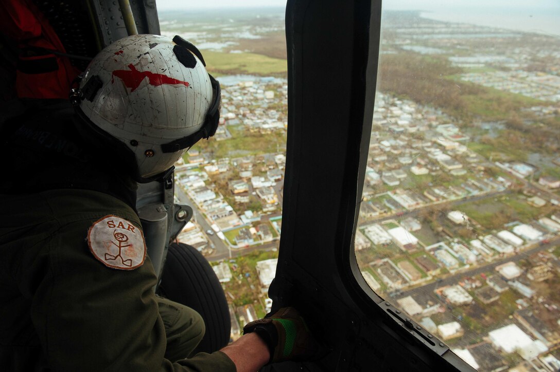 A sailor looks out the door of helicopter.