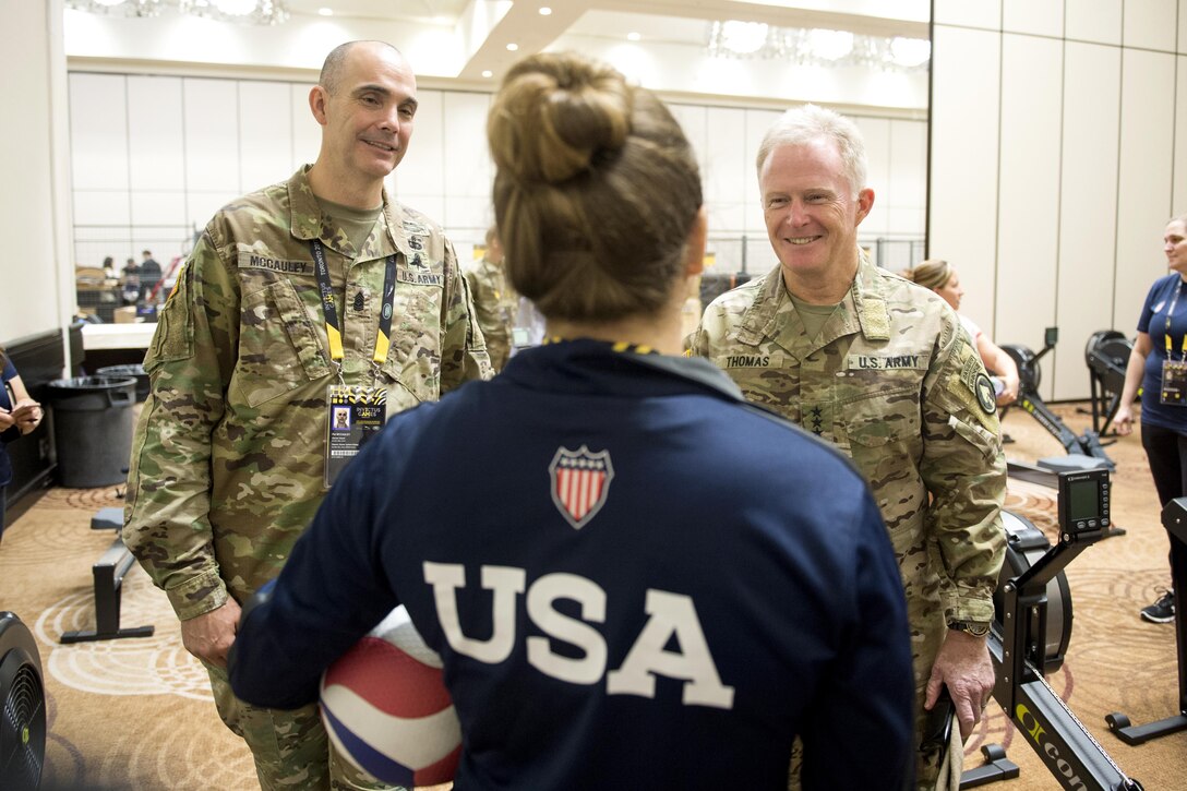Two soldiers speak to a member of Team U.S. in a room.