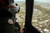 A sailor looks out the door of helicopter.