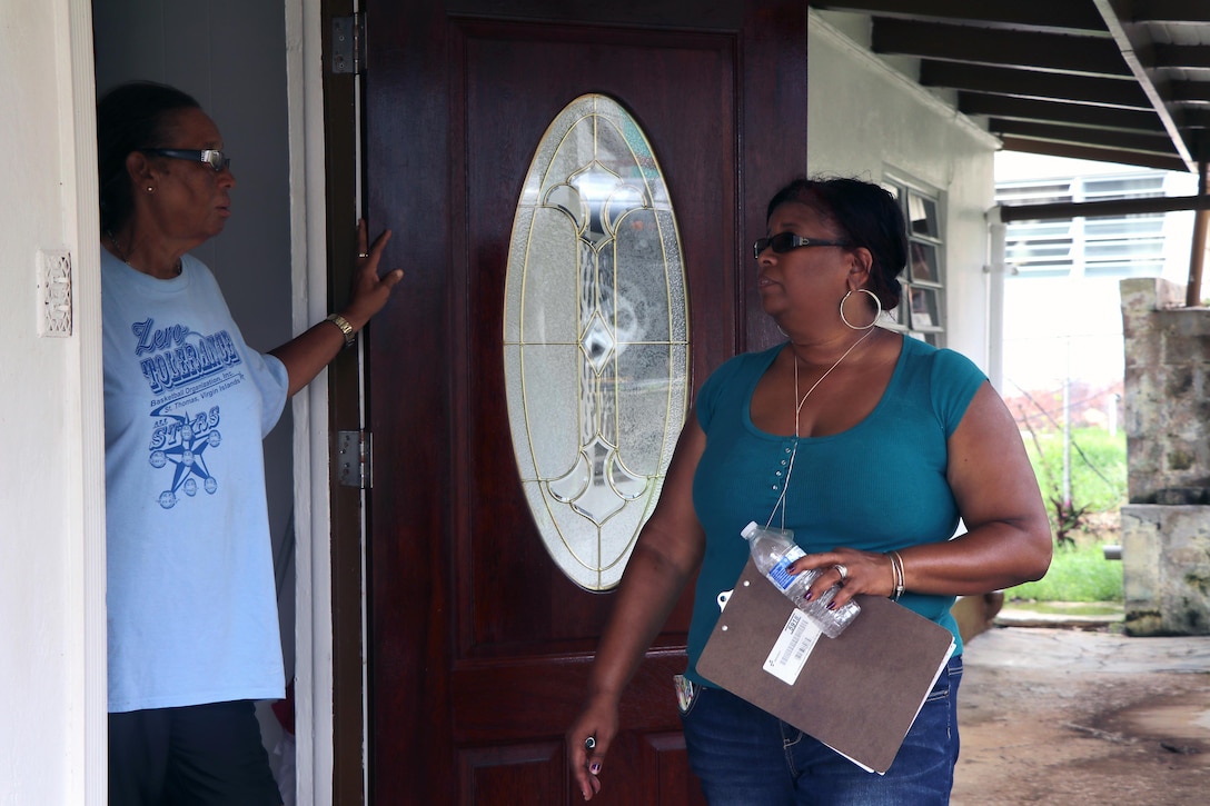 Department of Planning and Natural Resources Office Manager for Business and Administration Services talks to a home owner, helping Operation Blue Roof team members as they walk house-to-house. With five team members on the island, the Temporary Roofing Planning and Response Team is currently going house-to-house gathering Right of Entry forms. The forms allow Corps personnel on private property to assess homes and Corps contractors authority to repair the roofs. More Temporary Roofing team members are on their way. Operation Blue Roof’s purpose is to provide homeowners in disaster areas with fiber-reinforced plastic sheeting to cover their damaged roofs until arrangements can be made for permanent repairs.