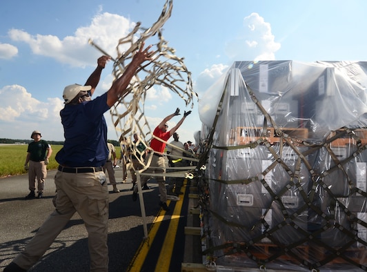 Department of Health and Human Services logistician throws a cargo net over a pallet on the flightline at Dobbins Air Reserve Base, Ga. Sept. 21, 2017. This cargo included items needed to build a hospital from scratch – everything from the tents required to house the temporary structure to the medical equipment used to treat patients. (U.S. Air Force photo/Don Peek)