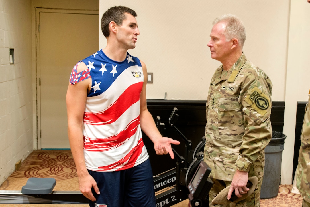 A military commander speaks to an athlete.