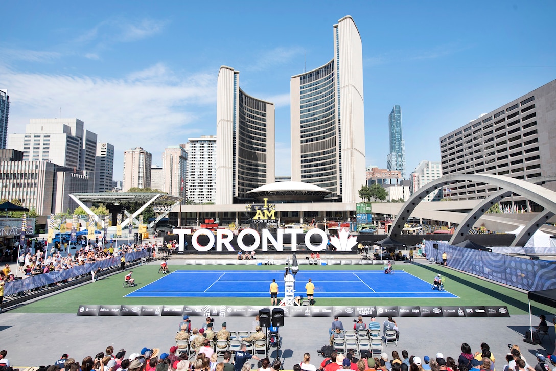 A broad look at a tennis stadium with city buildings in the background.
