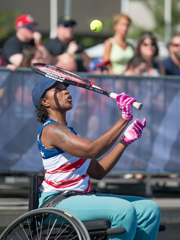 A wounded warrior serves a ball during a wheelchair tennis match.