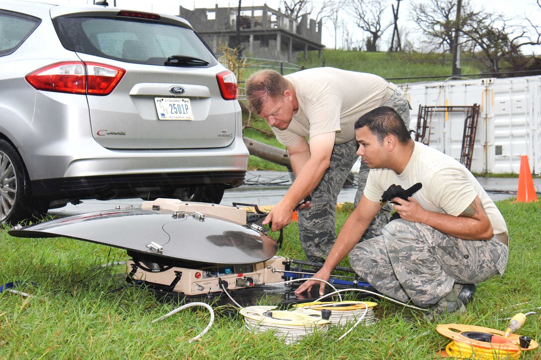 Two service members set up a satellite dish.