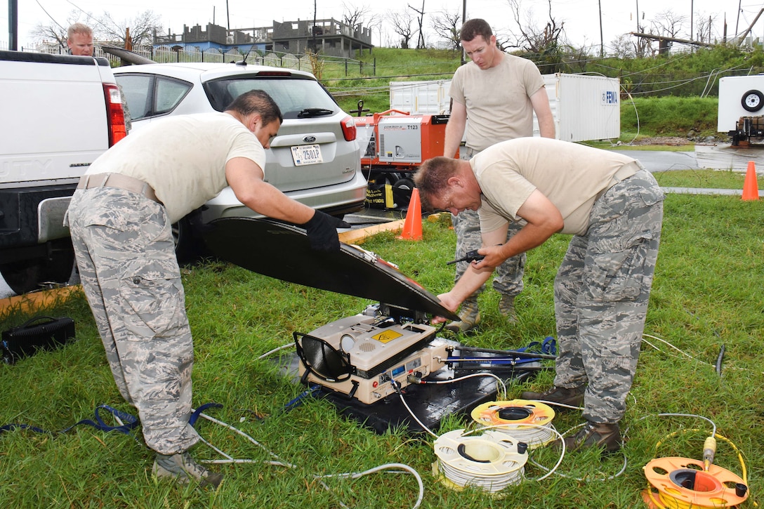 Guardsmen run antenna cable while setting up a satellite dish.