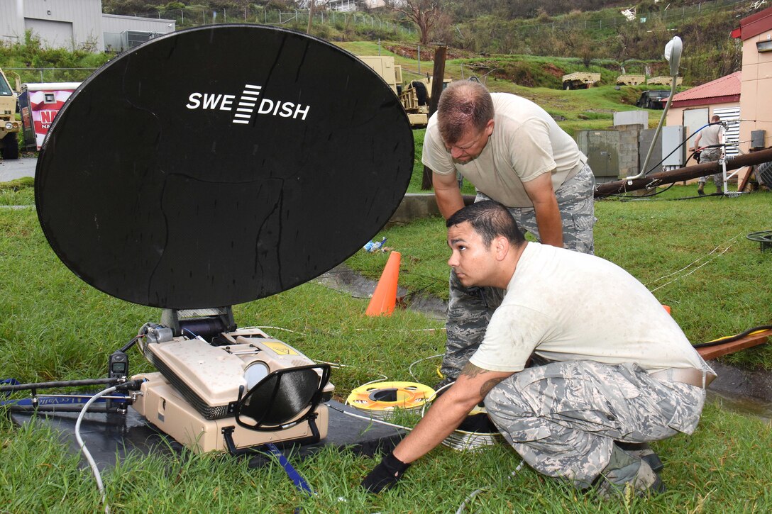 Service members set up a satellite dish.