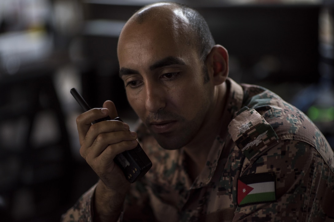 Royal Jordanian Air Force Lt. Burhan A S Aboelrob, joint defense operations center controller, communicates to Jordanian forces about a suspicious vehicle outside the installation, July 12, 2017, in Southwest Asia. U.S. and Jordanian service members work side-by-side in the JDOC to ensure base security. (U.S. Air Force photo/Senior Airman Damon Kasberg)