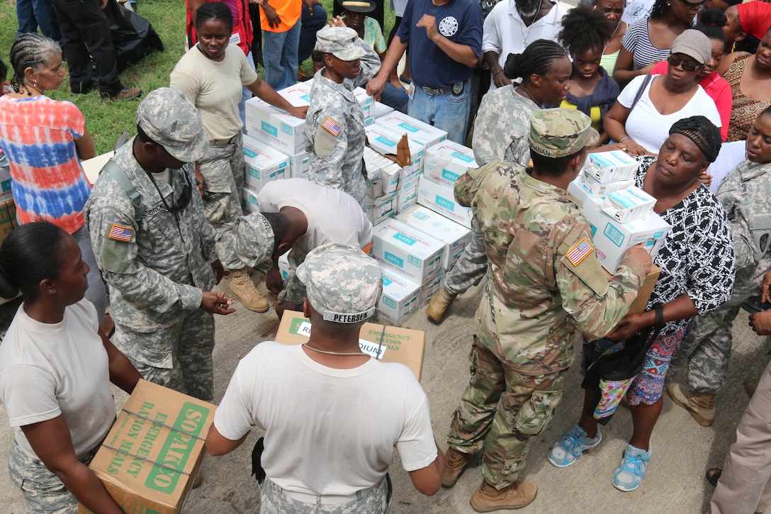 Guardsmen and members of the local fire department distribute food and water to residents.