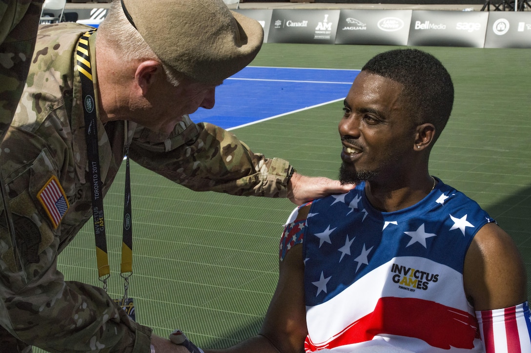 A military commander shakes hands with an athlete.