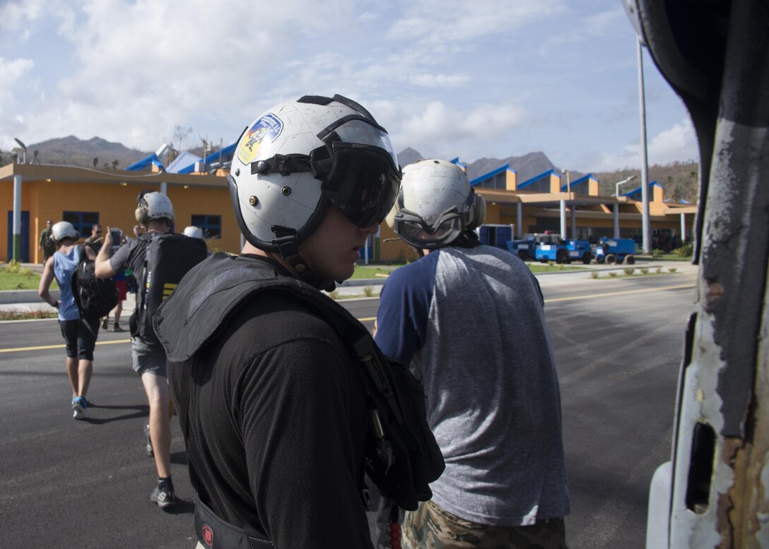 A U.S. Sailor guides U.S. citizens out of an MH-60S Sea Hawk helicopter during relief efforts in the wake of Hurricane Maria.