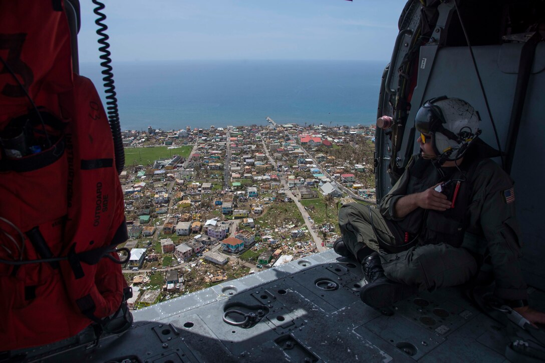 Naval Aircrewman (Helicopters) 2nd Class Logan Parkinson surveys damage over the island of Dominica following the landfall of Hurricane Maria.