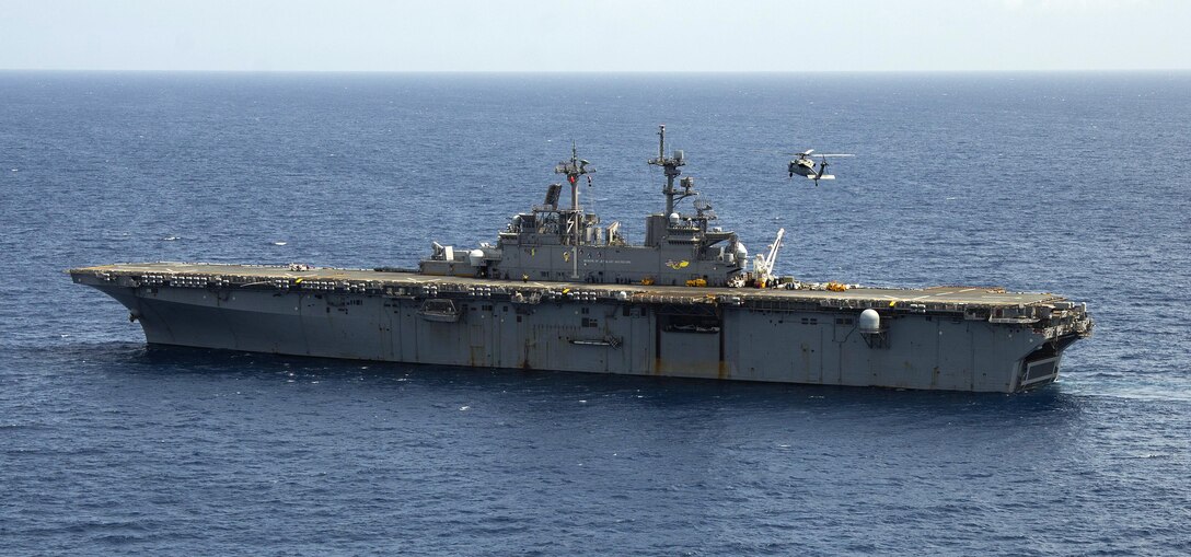 A helicopter approaches a ship in the water.