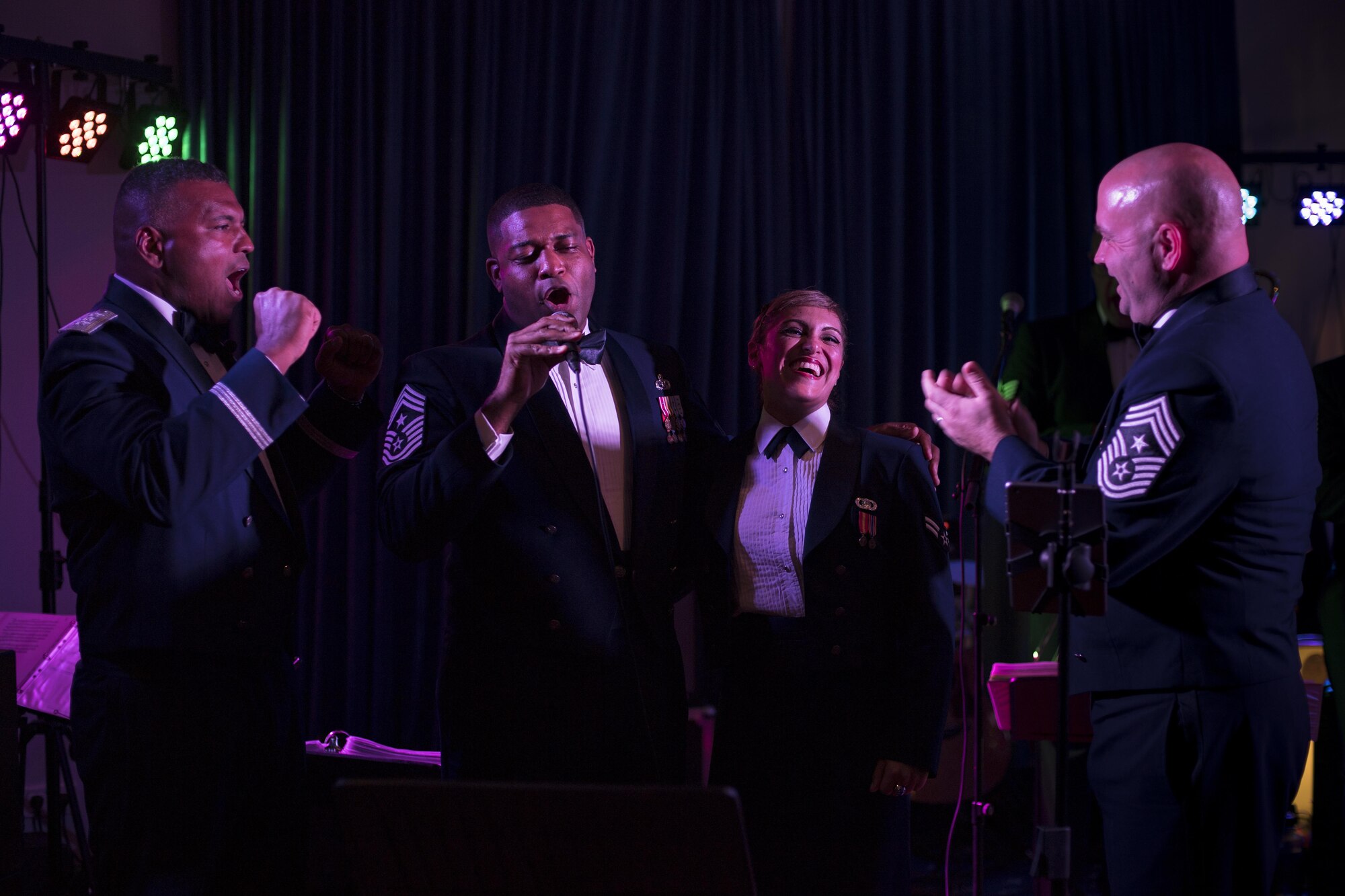 U.S. Air Force Lt. Gen. Richard M. Clark, 3rd Air Force commander, left; Chief Master Sgt. Phillip L. Easton, United States Air Forces in Europe and Air Forces Africa command chief, center left; Airman 1st Class Linda Casul, USAFE band’s Wings of Dixie regional band vocalist, center right; and Chief Master Sgt. Aaron D. Bennett, 86th Airlift Wing command chief, right, sing during the Air Force Ball at the officer’s club on Ramstein Air Base, Germany, Sept. 23, 2017.