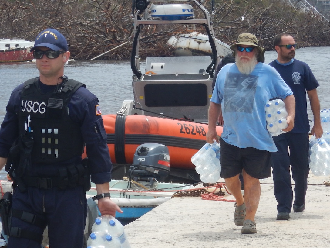 The crew of the Coast Guard Cutter Joseph Napier offloads 450 liters of water for the people of Coral Bay.