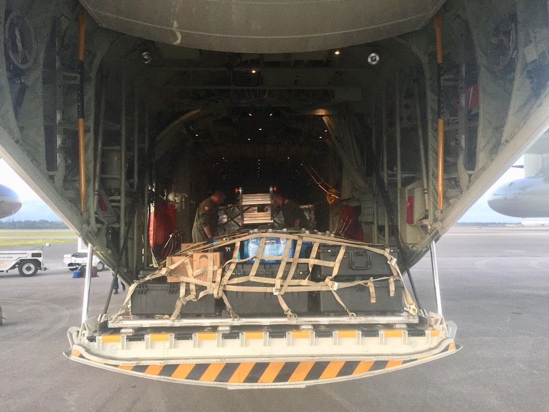 Coast Guard members load relief supplies onto an aircraft.