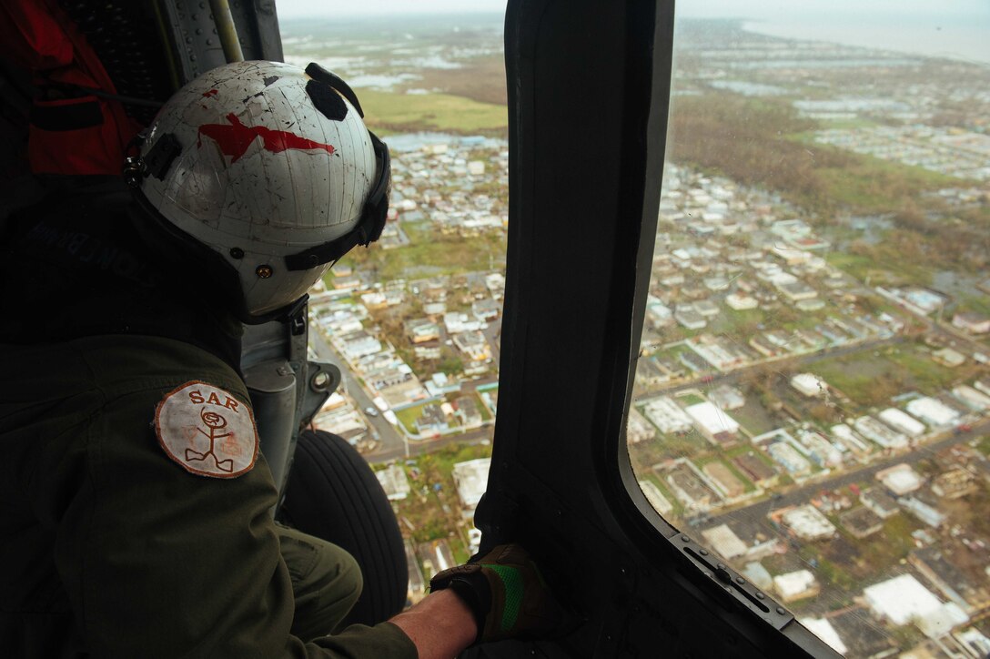 A Navy officer looks out of a helicopter during a search and rescue mission.