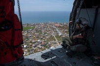 Naval Aircrewman (Helicopters) 2nd Class Logan Parkinson surveys damage over the island of Dominica following the landfall of Hurricane Maria.