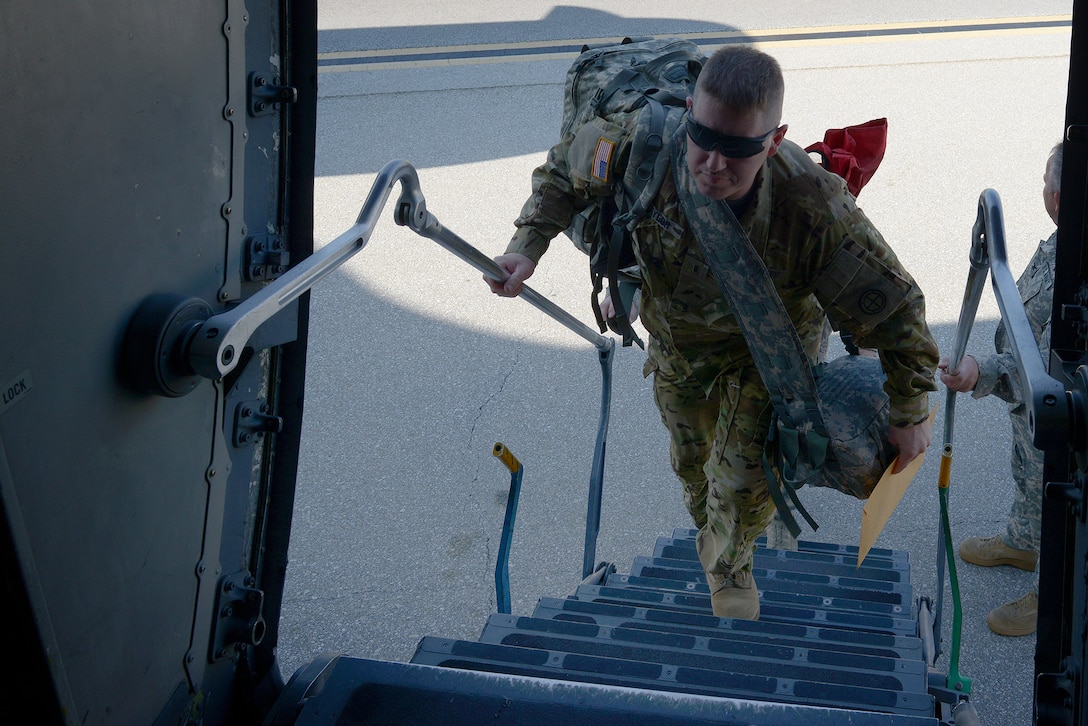 A soldier climbs the stairs into an aircraft.