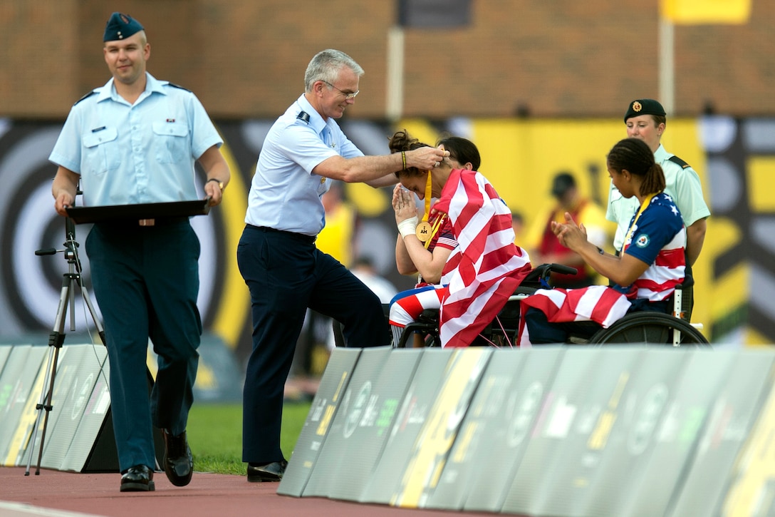 The vice chairman of the Joint Chiefs of Staff presents a gold medal to a Team U.S. member.