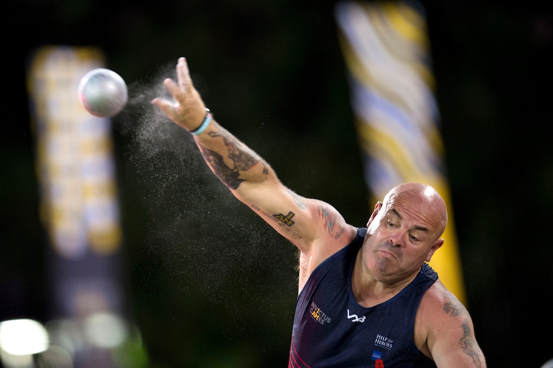 A Team Great Britain member throws a shot put .