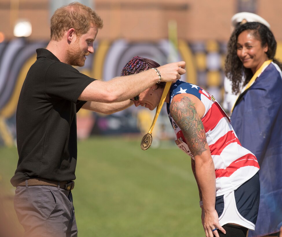 Prince Harry places a gold medal around the neck of a Team U.S. member.