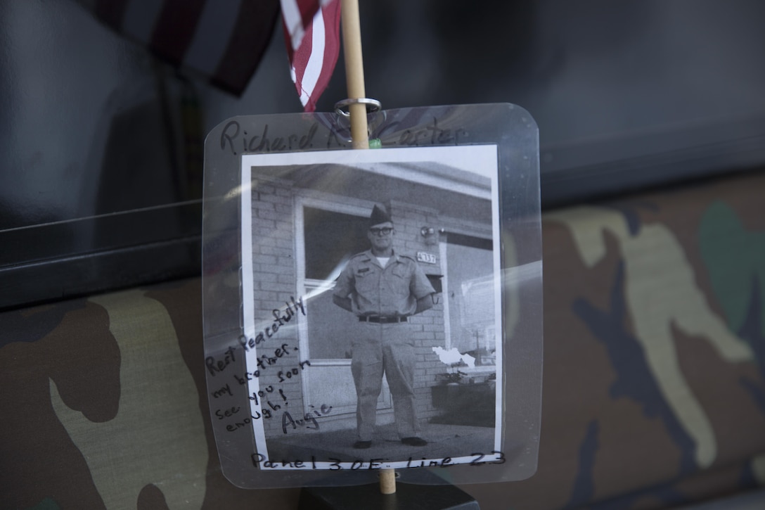 A picture of Sgt. Richard Carter, a soldier who died during the Vietnam War, rests in front of the Mobile Vietnam Memorial Wall, also known as the AV Wall, during the 2017 Marine Corps Air Station Miramar Air Show at MCAS Miramar, Calif., Sept. 22. Carter’s brother, Augie Anderson, is an AV Wall volunteer and placed the flag and photograph as a way to remember Carter, who died Nov. 19, 1967.  Anderson wrote “Rest peacefully my brother, see you soon enough!” (U.S. Marine Corps photo by Sgt. Lillian Stephens/Released)