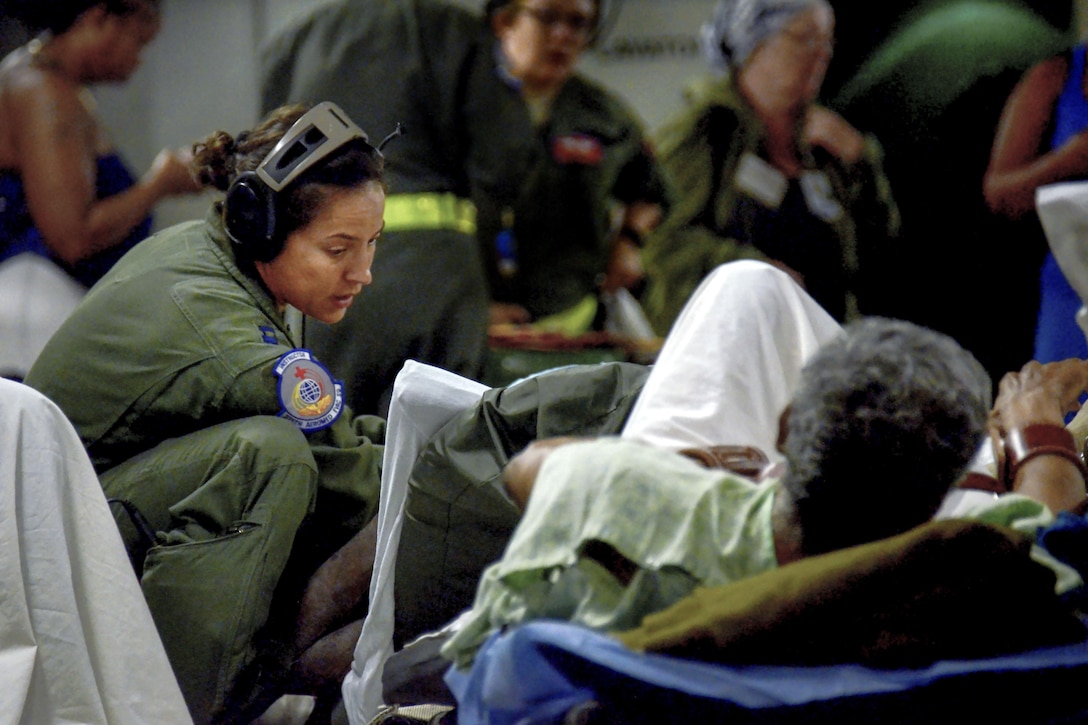 An airman tends to a patient on a stretcher aboard an aircraft.