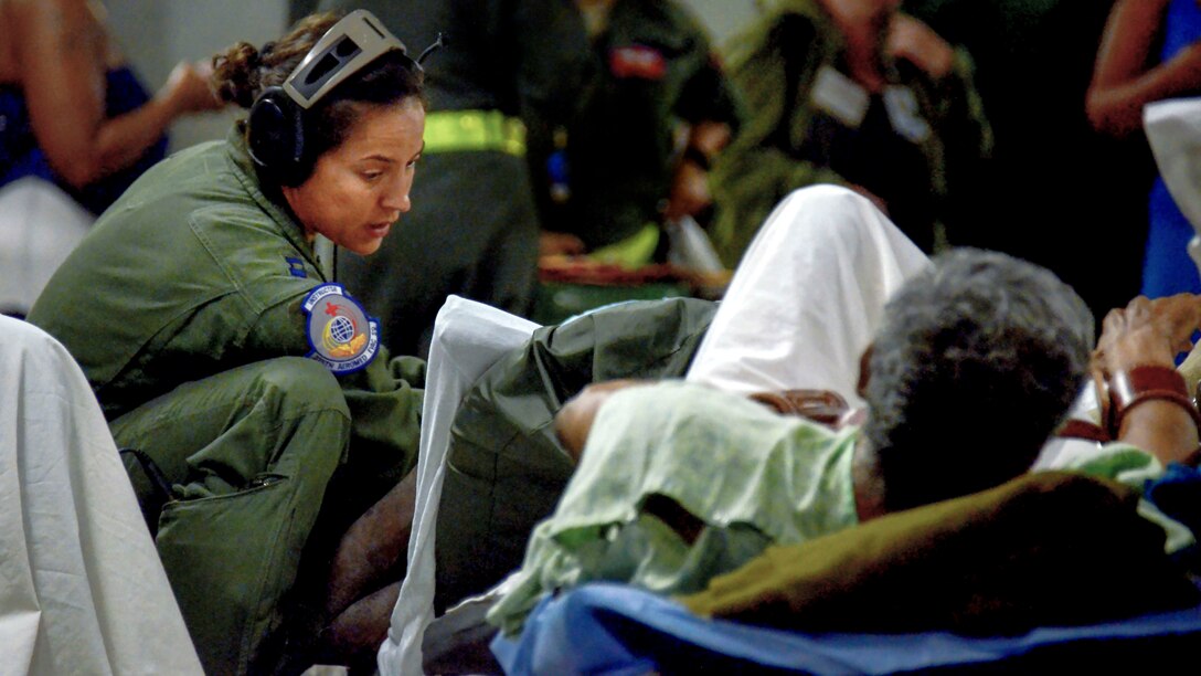 An airman tends to a patient on a stretcher aboard an aircraft.