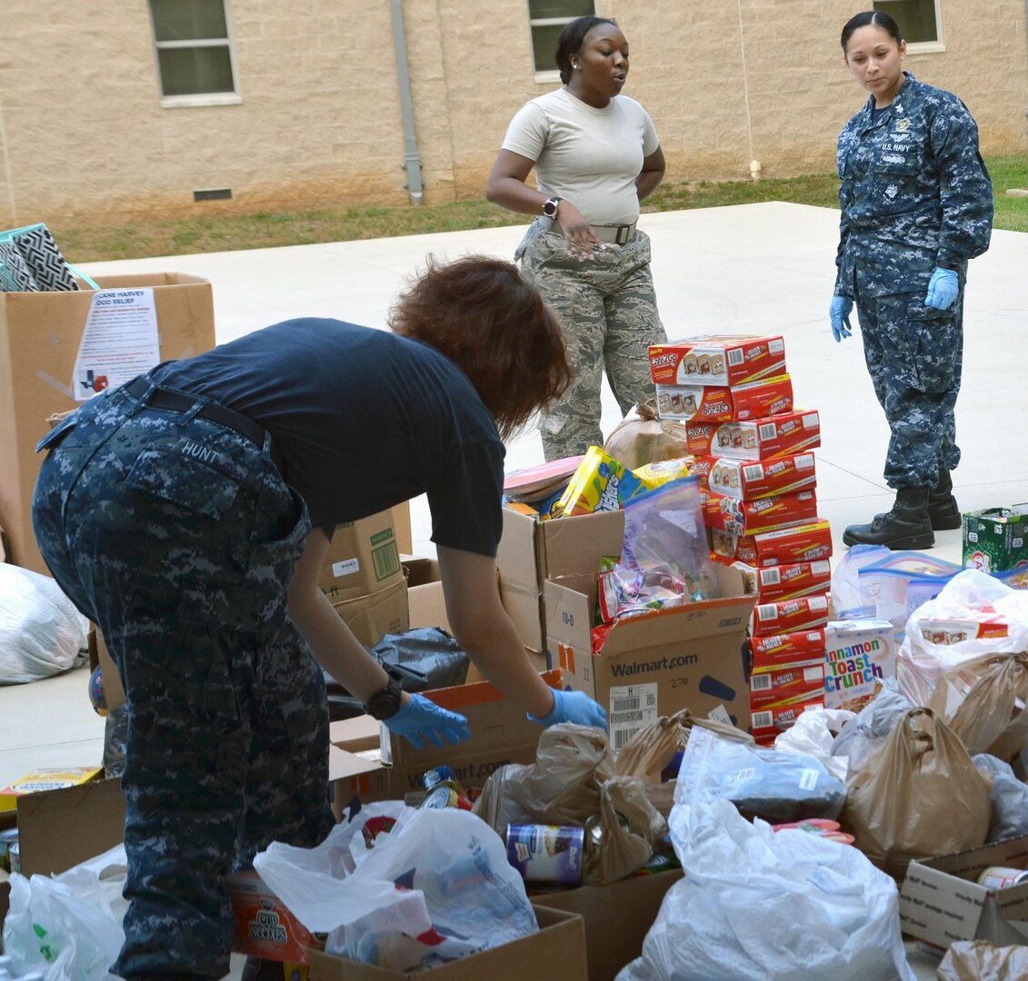 1st Lt. Ebony Shannon (center), Medical Education and Training Campus Support Center Information Technology Director, and Petty Officer 1st Class Alejandrina Alonzo, NMTSC Career Counselor, discuss plans for organizing the food donations collected for victims of Hurricane Harvey September 19. In all, the team collected and donated 450 pounds of food to the San Antonio Food Bank, $3,300 in donated diapers to the Diaper Bank, $19,000 in clothing and incidentals to the Salvation Army, and numerous donations to the American Society for the Prevention of Cruelty to Animals and homeless shelters.