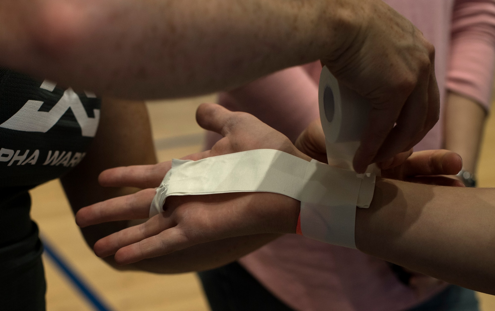 Barclay Stockett, Alpha Warrior pro, tapes the hand of a child during the Alpha WarriorTour on Ramstein Air Base, Germany, Sept. 22, 2017. Department of Defense card holders ages 13 and older were given an opportunity to run through the course before the local and regional competitions were held. (U.S. Air Force photo by Senior Airman Tryphena Mayhugh)