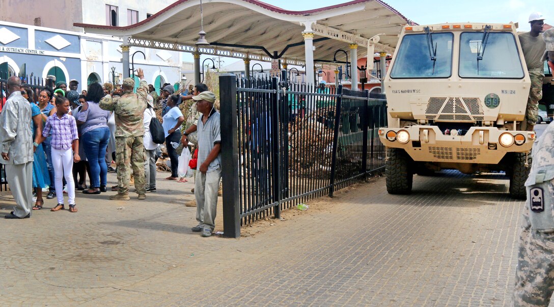 A military vehicle is surrounded by people.