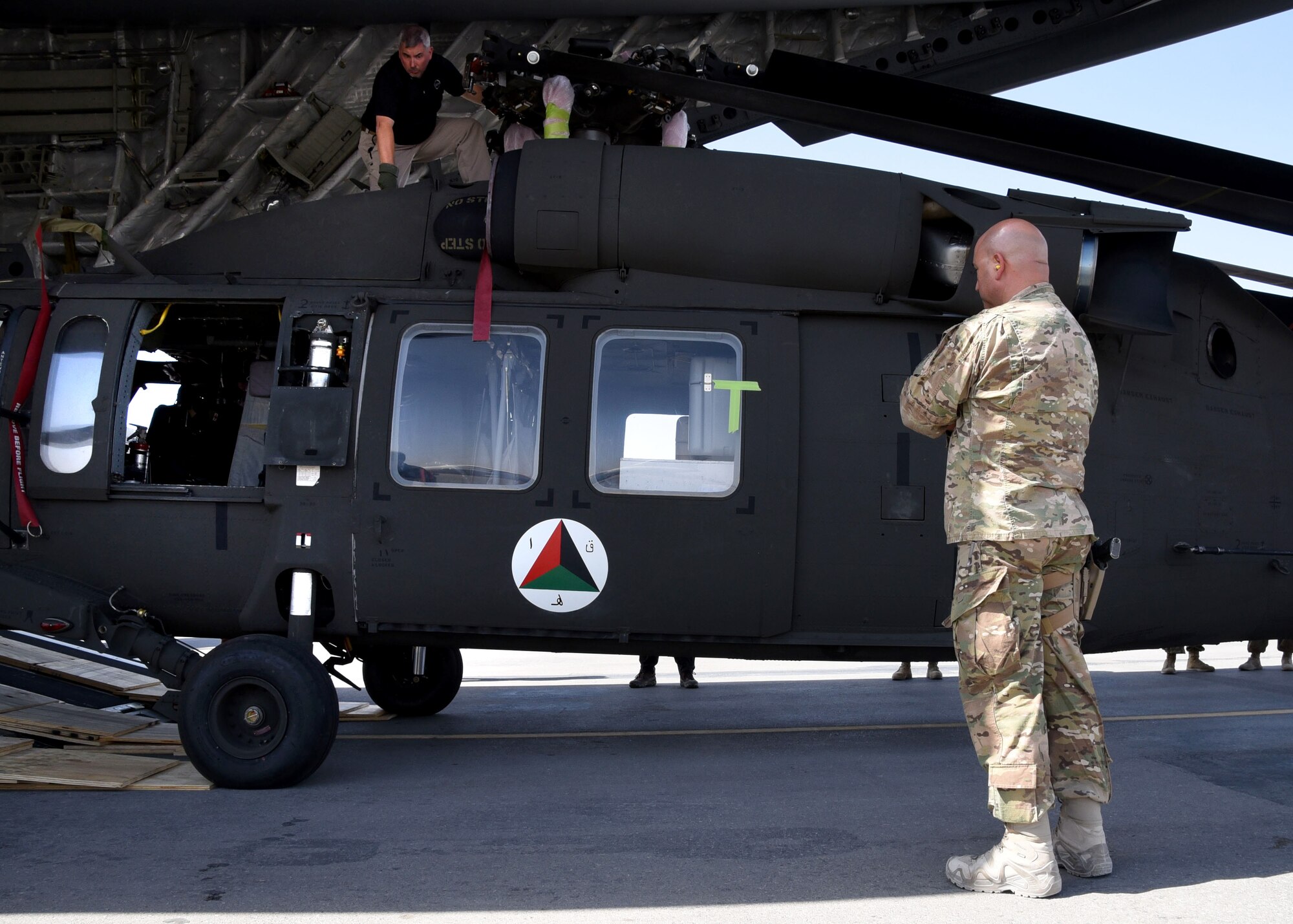 U.S. Air Force Col. Armando Fiterre, the 738th Air Expeditionary Advisory Group commander, Train, Advise, Assist, Command-Air, watches as the first Afghan Air Force UH-60 helicopter is unloaded off a U.S. Air Force C-17 Globemaster, Sept. 18, 2017, at Kandahar Air Field, Afghanistan. The UH-60 arrival is part of the recapitalization efforts of the AAF. The plan involves seven different weapon systems, 14 program offices and more than 20 major contracts. TAAC-Air will oversee training of AAF pilots and maintainers. (U.S. Air Force photo by Tech. Sgt. Veronica Pierce)