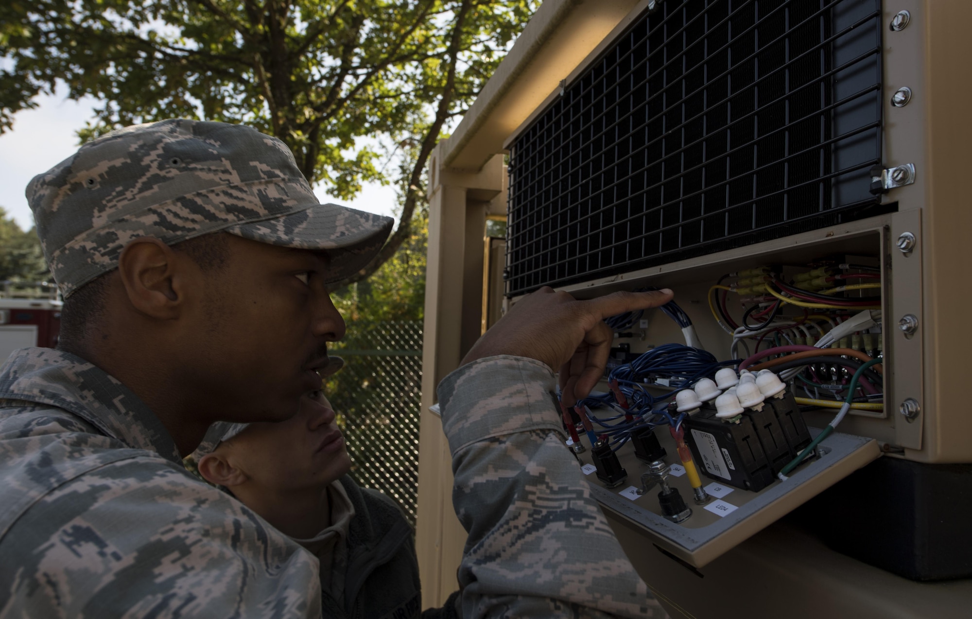 U.S. Air Force Senior Airman Theriot Moore, 786the Civil Engineer Squadron heating, ventilation, and air conditioning journeyman, examines the wiring of a tricon refrigerated container system to repair it during the 86 CEG Prime Base Engineer Emergency Force training day on Ramstein Air Base, Germany, Sept. 21, 2017. The Prime BEEF training day included sessions in CPR, night vision goggles, operating a Humvee, tent assembly, and heating, ventilation, and air conditioning. (U.S. Air Force photo by Senior Airman Tryphena Mayhugh)