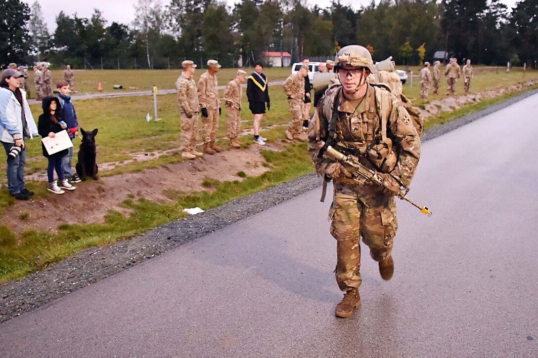 A soldier prepares to cross the finish line participating in a 12-mile ruck march.
